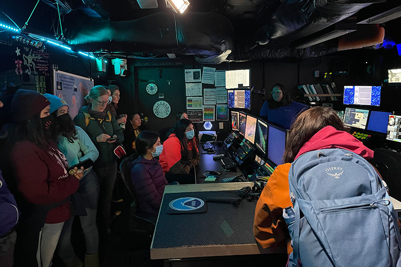 Shannon Hoy, expedition coordinator team lead with NOAA Ocean Exploration, briefs a group of interns from the Alutiiq Museum/Center for Alaskan Coastal Studies in the control room of NOAA Ship Okeanos Explorer.