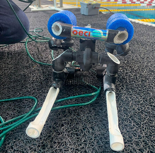 A small remotely operated vehicle (ROV) on a pool deck at a student ROV competition.