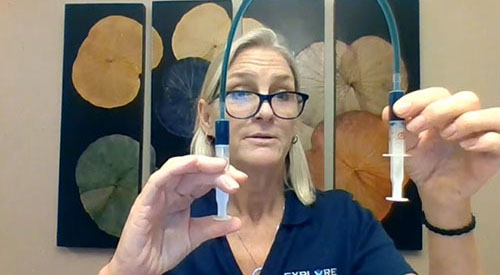 NOAA Ocean Exploration Education Team Manager, Susan Haynes, demonstrates construction of a simple hydraulic actuator using two oral syringes, a short length of aquarium tubing, and water (dyed green).