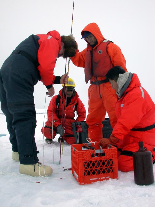 The nutrients team lower the primary productive sampling equipment into the ice