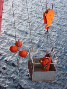 A crew member inspects the instrumentation and buoy setup for a mooring deployment