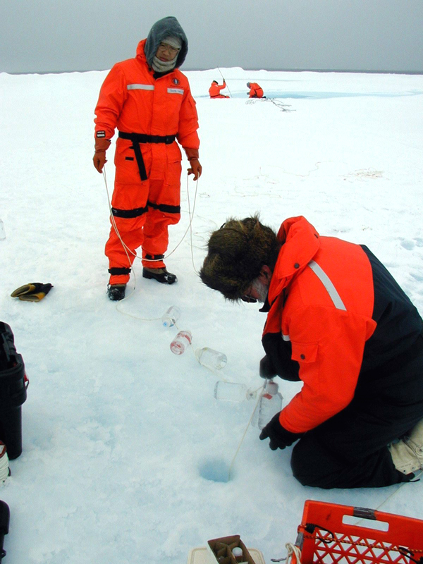 Scientists lowering sample bottles below ice