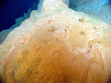 Yellow and orange microbial mats forming bioreactor mound with a thin crust and small chimneys on top.