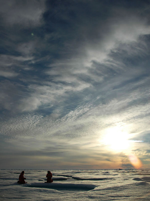 Scientists gather samples from a sea ice melt pond in the middle of the Arctic night