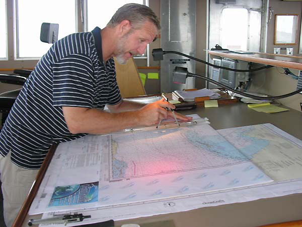  First Mate Mike Schoeller checks his charts to confirm the ship's faster-than-expected transit time to its first dive location.