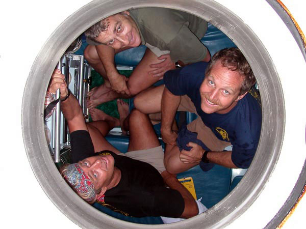 The explorers of the Pisces V look up from inside the hatch of the submersible before a dive.