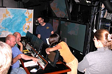 Pamela Lezaeta of the Institute for Exploration coordinates a review of operations in the control van while Timothy Shank, of the Woods Hole Oceanographic Institution, Peter Auster, of the University of Connecticut, Scott France, of the University of Louisiana, and Celeste Mosher, of the University of Maine look on.