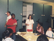 At the artifact storage facility inside of Naval Station Norfolk, Tracey, Jazmine, Darius, Marena, Nicole, Morgan and Derrick present their findings