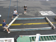 The frame of the MOC 10 trawl is bolted together on the dock next to the ship.