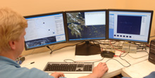 AUV technicians watch the navigational tracks of three AUVs from an office onshore.