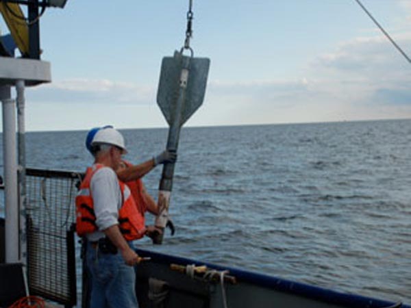 Scientist removes sediment sample from the gravity core for later analysis.