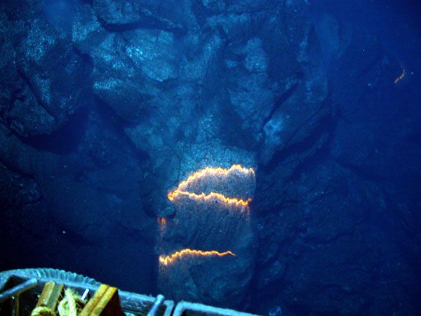 The orange glow of superheated magma, about 2,200 degrees Fahrenheit, is exposed as pillow lavas extrude from the eruption. 