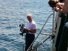 Principal Investigator, Dr. Adovasio, hands off an underwater video camera to divers. 