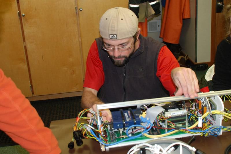 Prior to launch, Jeremy Taylor double checks the inner workings and wiring of the AUV to ensure clear communication between the vehicle and the surface during the dive.