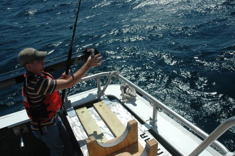 Clinton Johnson takes a sound velocity profile using a device that records temperature at multiple points, as it sinks to the bottom.