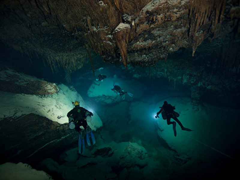 Brian Kakuk, Paul Heinerth, Brett Gonzalez and Tom Iliffe, all using sidemount system, swim in a Big Room of Deep Blue Cave, Walsingham System.