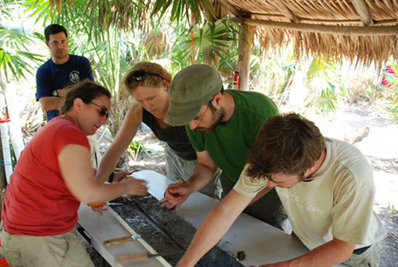 The team works together to carefully open up one of the core collected at Vista Alegre. Cores were cut length-wise using a small circular saw and then carefully pried apart with tools to split the sample into two equal parts.