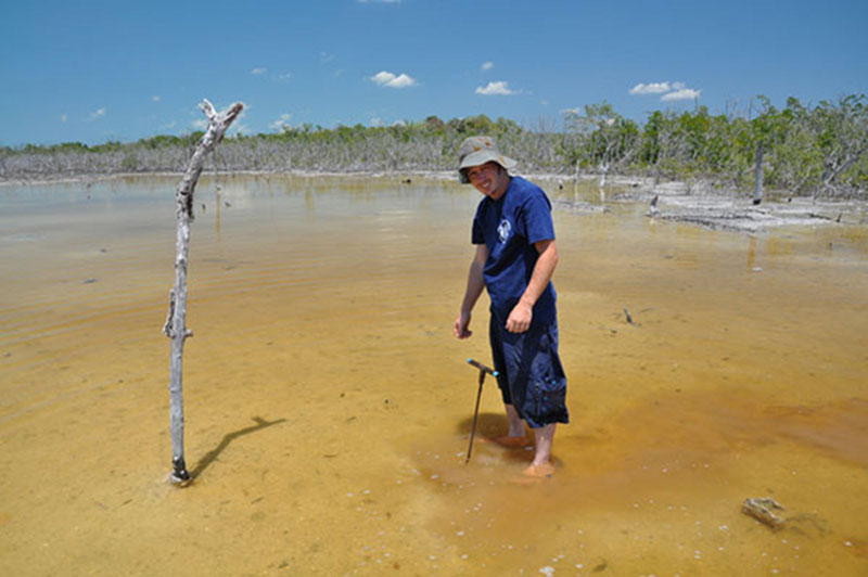 Conducting a preliminary survey of potential coring sites around Vista Alegre, Dan Leonard sinks a metal probe down into the sediments to estimate depth.
