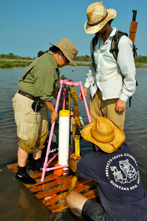 Trish Beddows, Jeffrey Glover and Dominique Rissolo use the pink tripod and portable coring platform to remove a sediment core taken in shallow, hyper-saline waters near Vista Alegre.