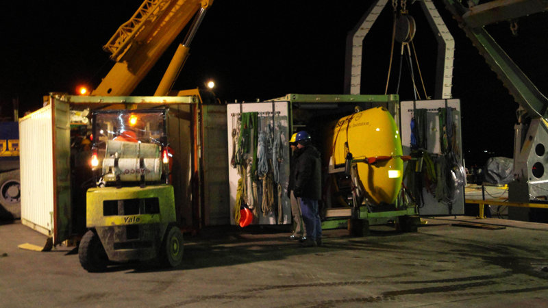 Sentry (on the right) has already been slid out of its van far enough to be ready for a crane-lift aboard ship. Now, TowCam is about to be pulled out of the left-hand van as Tim (yellow hat) and Greg (blue) look on. Note the shoulder-high size of the wheel for the 70-ton crane visible to the left of, and behind, the TowCam container – that’s a serious-sized piece of equipment!