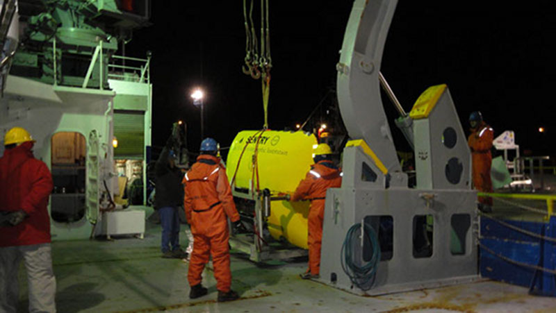 Sentry coming aboard. Andy, who is head of all our Sentry deck operations, looks on from on shore (far right) while Tim (in his new black coat) give instructions. John (blue hat) and Justin (yellow hat) are the other people in this photo doing the serious work (and sporting bright orange “Mustang” suits like Andy’s. I’m the one in the red coat keeping well back and out of trouble (I know my place).