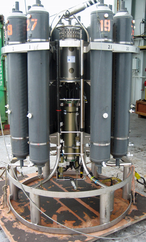 A closeup of a CTD, the primary tool used to map hydrothermal plumes. A ring of plastic sampling bottles surrounds the CTD. The bottles are closed on command from the ship, usually when a scientist monitoring the sensors sees strong evidence of a plume. CTD sensors are visible at the bottom of the pressure case.