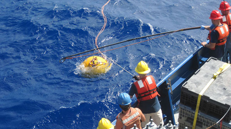 Scientists and crew on starboard side of R/V Roger Revelle standing by to recover the buoy and mooring.