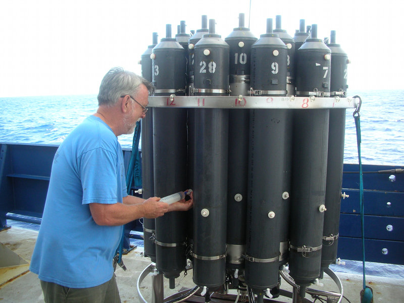 Scientist on board R/V Roger Revelle extracts water from one of the sample bottles in the CTD rosette.