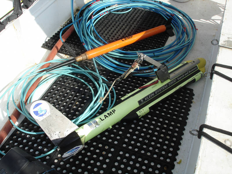 The orange magnetometer tow fish (above) and the side scan sonar tow fish (below) with their bundled tow-cables that carry power and data between the instruments and computers on the boat.