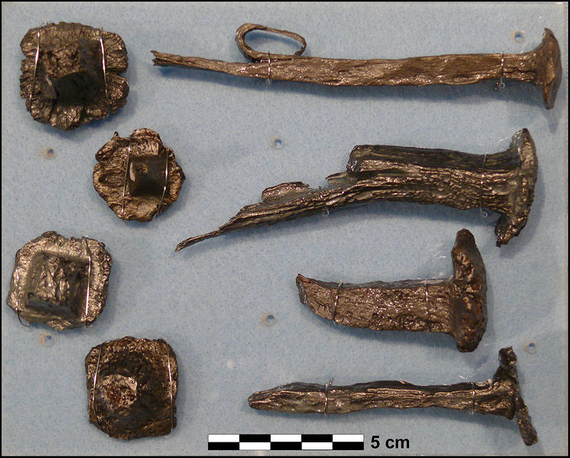 Iron artifacts recovered from the Armstrong Site that were salvaged from wreckage and modified by 1565 shipwreck survivors. At left, there are four examples of ship’s fastener heads which have been cut from their shanks by saw or chisel. Many examples were found, and they for the most part represent debitage from tool making using a forge and tools. Some could have been meant to form hammer heads by insertion into the striking face of a wooden mallet. At right are partially intact ship’s spikes. Each displays clear evidence of using a forge to heat and then tools such as saws, hammers, chisels, anvil, and clamps to remove stock iron for use in constructing new tools.