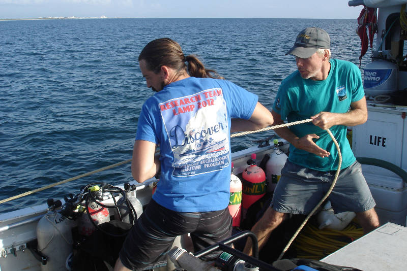 Brian McNamara, left, and Sam Turner, right, haul in on the stern anchor line.