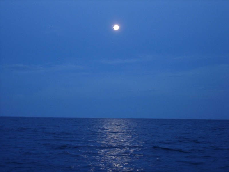 The full moon rises above the broad Atlantic Ocean.