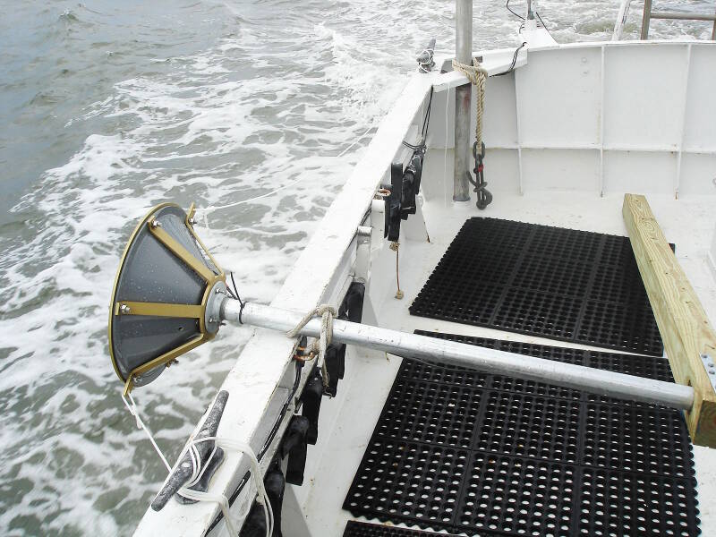 The transducer for the subbottom profiler, secured on the gunwale while the boat is underway. The cone-like transducer will be lowered straight down into the water during survey, so that it can send soundwaves directly down into the seafloor to potentially “see” buried wreckage.