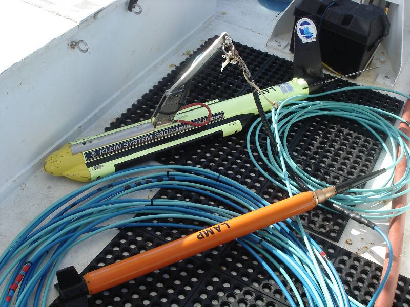 The yellow, torpedo-like object is our sidescan sonar fish, a Klein System 3900. The slender orange unit is the Marine Magnetics Explorer Mini-Magnetometer.