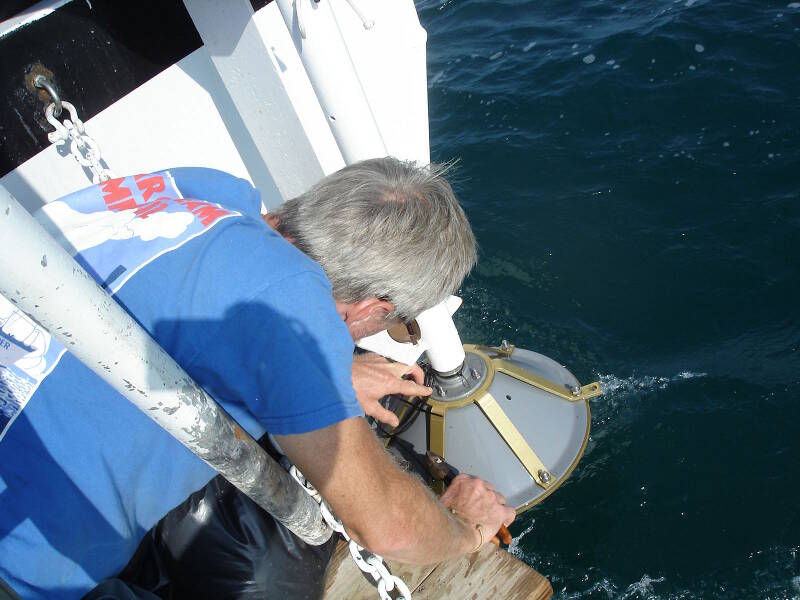 Dr. Turner securing the subbottom transducer at the stern of the boat. When deployed, it is lowered into the water where it sends its sonar pings down into the seafloor below.