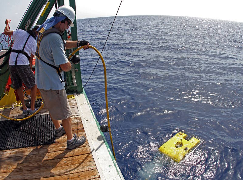 Lance Horn manages the tether as the remotely operated vehicle moves away from the research vessel after hitting the water.