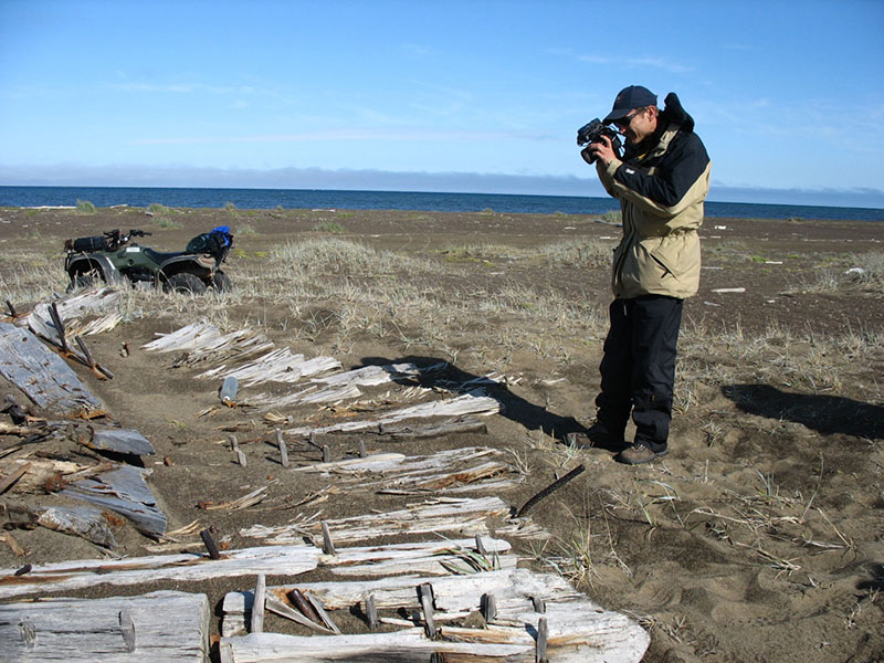 Randolph Beebe documenting a large bow section of a wooden whaling vessel found along the shoreline.