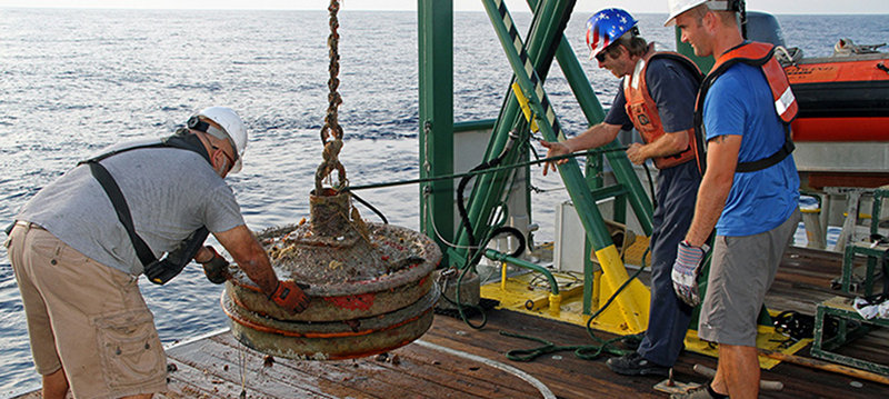 The excellent work of the crew of the R/V Walton Smith was instrumental in today’s successful recovery of the physical oceanography moorings. At this site, Electronics Technician Dennis Ilias, Chief Engineer Mike Shoup, and First Mate Steve Deschenes (left to right) are near the end of the recovery, safely placing on the deck railroad wheels that weigh 700 pounds each!