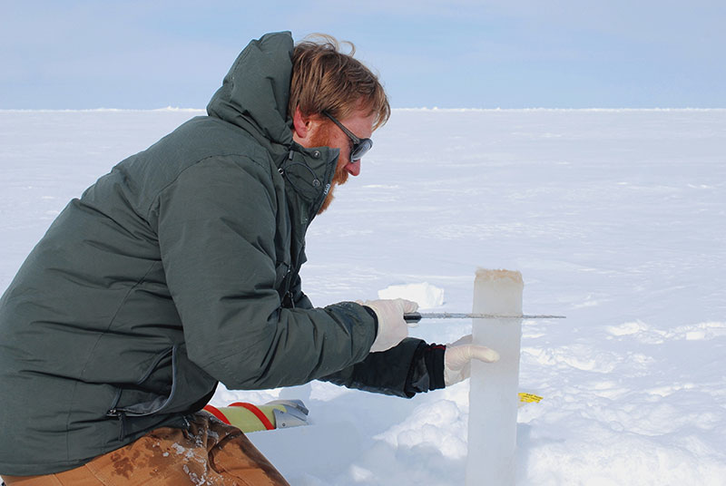 Eric Collins cuts off the bottom of a sea ice core containing sea ice algae.