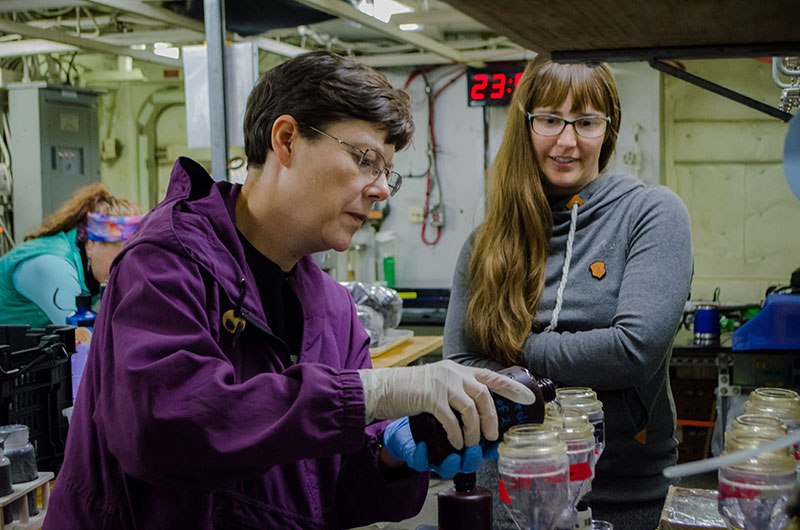 Alexis Walker observes as Sandra Thornton assists with filtering water collected from the CTD.