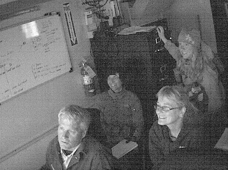 A night vision camera in the ROV control van captures the excited faces of Joe Caba, Dr. Katrin Iken, Lauren Sutton, and Kelly Walker as they watch the live camera feed from the ROV Global Explorer as it explores the Arctic seafloor.