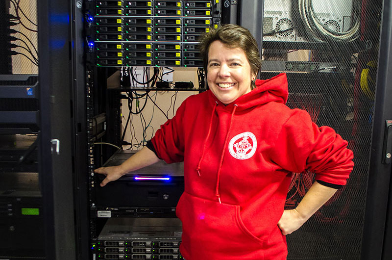 Sarah Kaye stands in front of the system that provides Internet for the entire ship.