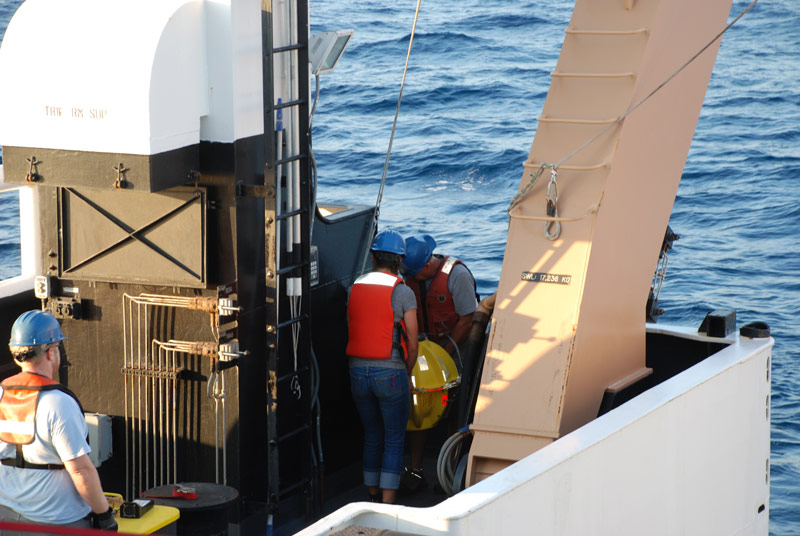 Mike McCarthy and Molly Curran of the AUV team carry the stationary transponder to the stern of the ship for deployment.