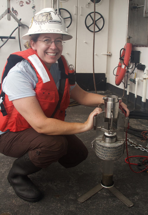 Amanda holds a monocore, an instrument used to collect a discrete sample of the bottom sediments.