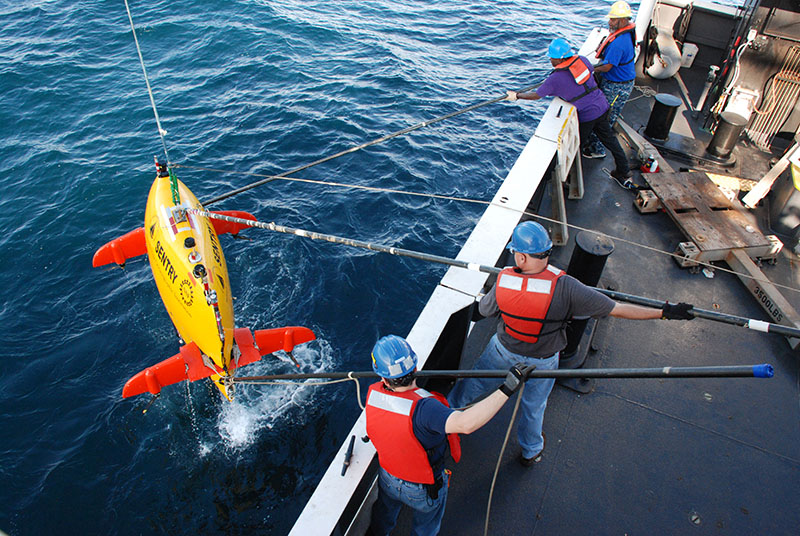 Sentry engineers (bottom, Ian Vaughn and Andy Billings) and the ship’s deck crew (GVA Fountain and CB Walker) work to secure tag lines on the vehicle. Once secured, these lines help them to steadily guide the Sentry onto the deck and into its cradle.