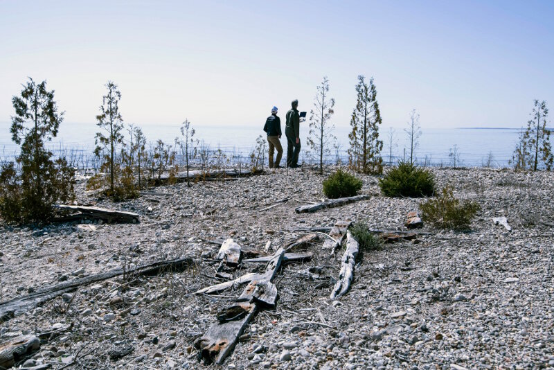 Pilots Matt Pickett and Brian Taggart observe a UAS during a survey mission over Thunder Bay’s North Point Reef; beached shipwreck remains are scattered throughout the foreground. 