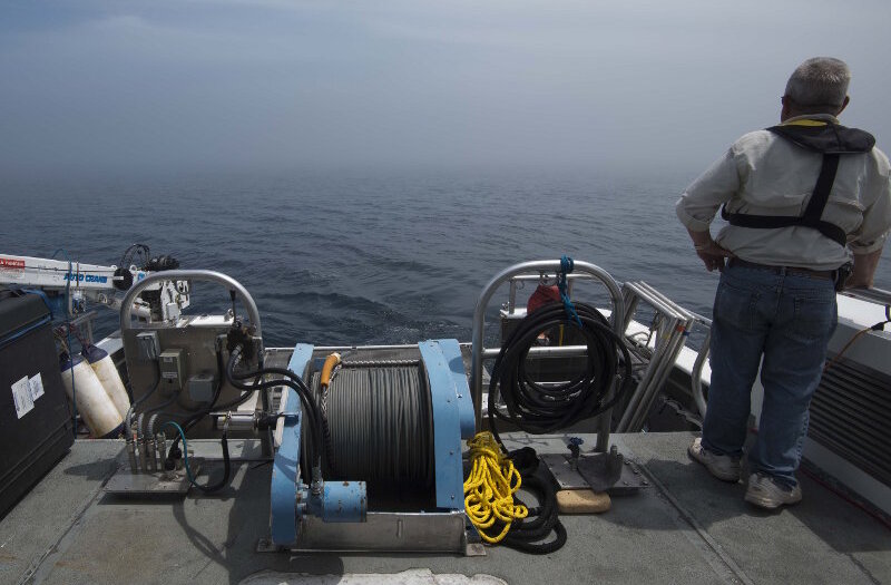 Project PI Dr. Guy Meadows looks across the lake surface into a dense fog surrounding R/V Storm. As the AUV missions progressed, the vehicle would periodically surface to update its GPS position. In addition to establishing a wireless connection, the survey team would also attempt to get visual confirmation of the vehicle’s status. This was extremely challenging, however, when socked in with fog.