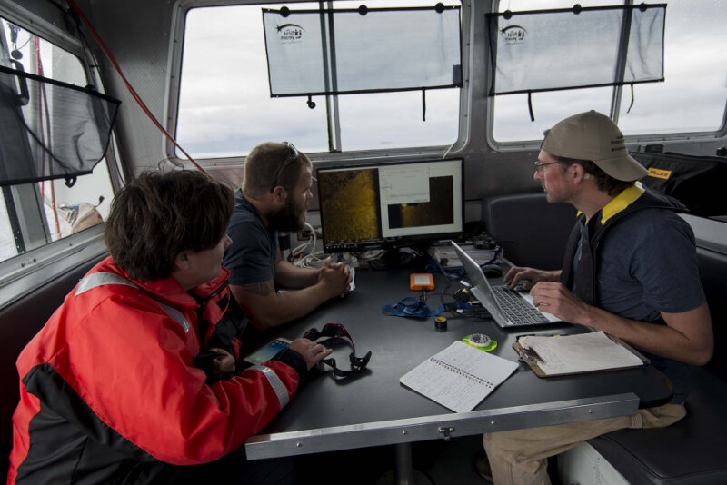 Maritime archaeologists John Bright and Stephanie Gandulla review sonar data with MTU’s Chris Pinnow following an AUV mission over bulk carrier Norman.