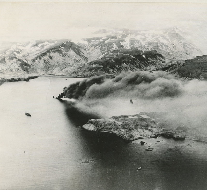 The 474-feet long Japanese transport ship Nisan Maru sinking in the middle of Kiska Harbor after it was stuck by bombs dropped by the US 11th Air force on 18 June 1942. Two other Japanese ships are visible in the harbor nearby.