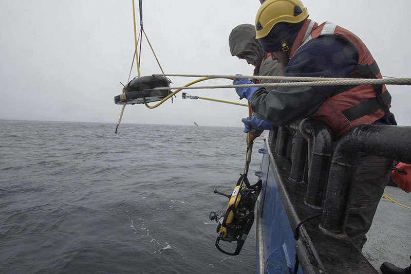 Team member Matt Breece lowers the project ROV over the side of Research Vessel Norseman II.